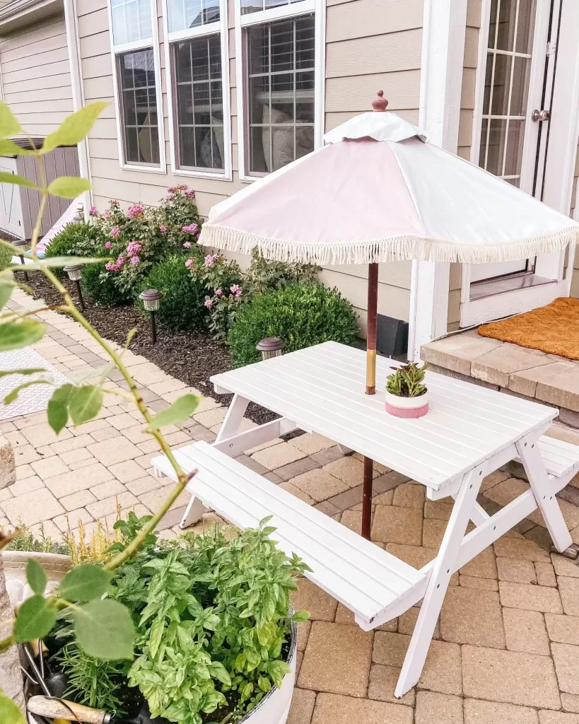 white childrens picnic table with bamboo umbrella painted pink, backyard paver pation with unilock cobblestone, brussels and hollandstone