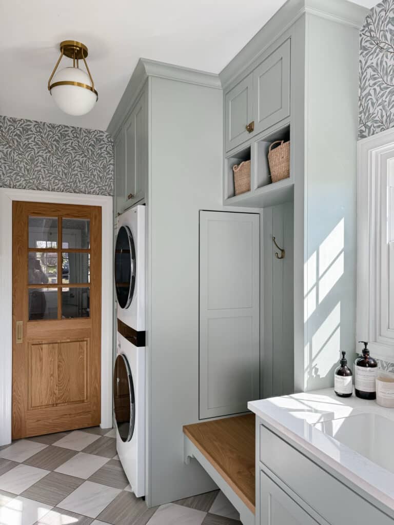 Green laundry room with checkered floor and botanical print wallpaper, laundry room ideas with stacked washer and dryer, laundry room ideas stacked, remodeled laundry room, Checkered floor tile, checkered floor, ceramic checkered floor, inset cabinets, green cabinetry, sherwin williams comfort gray